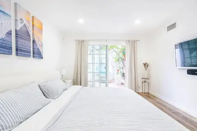 a white bedroom with a large bed and a window at New luxury entertaining house with Pool Spa Sauna Tesla charger Pets in Los Angeles