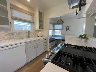 a kitchen with white cabinets and a stove top oven at El Nido Beachlife Cottage in South Bay Los Angeles in Redondo Beach