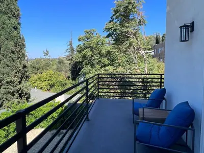 a balcony with blue chairs and a view of trees at Gorgeous Private and Gated Home in Silver Lake with Pool & Views in Los Angeles
