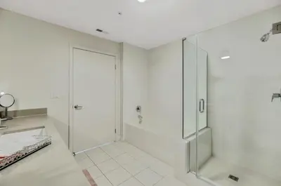 a white bathroom with a shower and a glass door at 5 Heart of Santa Monica apartment in Los Angeles