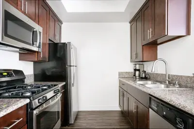 a kitchen with wooden cabinets and a black refrigerator at Hollywood 1BR w Gym Pool Spa nr Sunset LAX-55 in Los Angeles