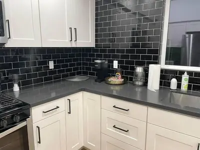 a kitchen with white cabinets and a black tile wall at Gated private house with own parking Sherman Oaks in Los Angeles