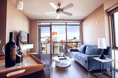 a living room with a blue couch and a large window at Masterpiece 2-Bedroom with Balcony, Pool, and Spa in Los Angeles