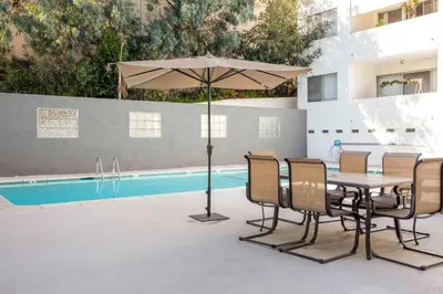 a table and chairs with an umbrella next to a pool at Brentwood 1BR w Outdoor Pool nr UCLA Downtown LAX-188 in Los Angeles