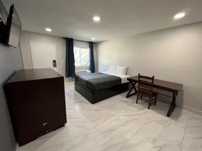 a bedroom with a bed and a table and a desk at Goldstar Inn in Los Angeles