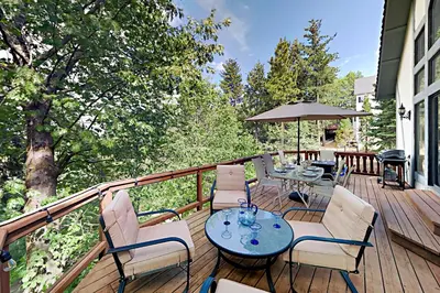 a deck with chairs and tables and an umbrella at Emerald Oasis in Lake Arrowhead