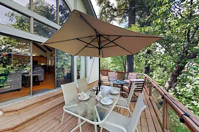 a table and chairs on a deck with an umbrella at Emerald Oasis in Lake Arrowhead