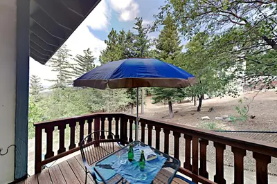 a table with a blue umbrella on a deck at Emerald Oasis in Lake Arrowhead