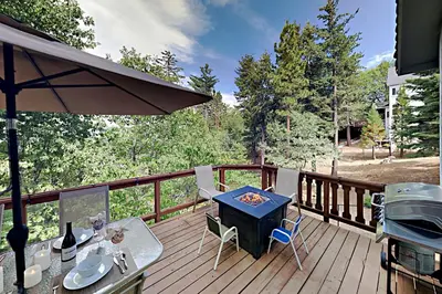 a patio with a table and chairs on a deck at Emerald Oasis in Lake Arrowhead