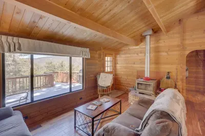 a living room with a large window in a log cabin at Pine Mountain Club Cabin Rental with Pool Access! in Pine Mountain Club