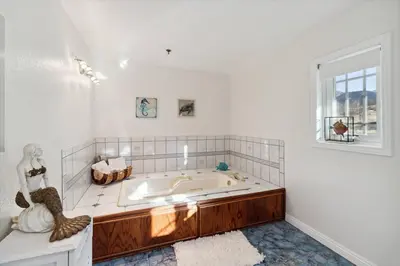 a white bathroom with a large tub with a window at The Big Sky in Pearblossom