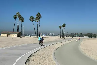 two people riding bikes on a bike path on the beach at The Heart of Belmont Shore in Long Beach