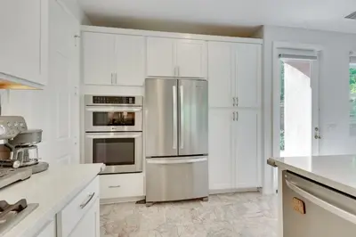a kitchen with white cabinets and a stainless steel refrigerator at Family-Friendly Camarillo Home with Access to Pools! in Camarillo