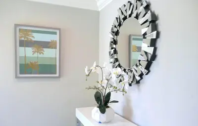 a mirror on a wall next to a vase with flowers at Disneyland Paradise 6 BedRoom 4 Bathroom Pool Spa Games in Anaheim