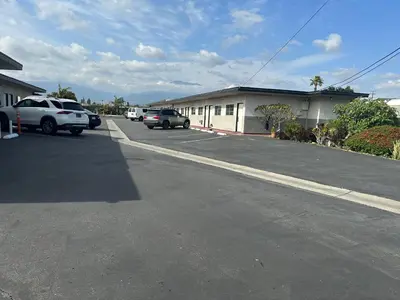 a parking lot with cars parked in front of a building at Rancho Motel - Ontario Airport in Ontario