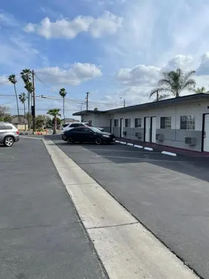 a parking lot with two cars parked in front of a building at Rancho Motel - Ontario Airport in Ontario