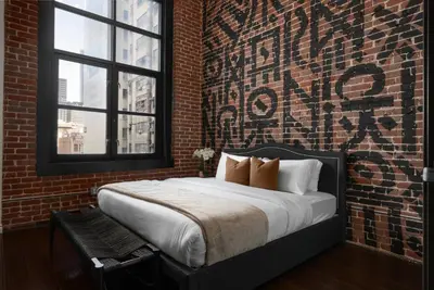 a bedroom with a large bed with a brick wall at Audemar Boutique Hotel and Apartment Homes in Los Angeles