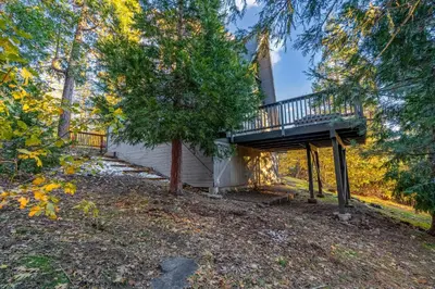 a tree house with a deck in the woods at Hot Tub-EV-Kid Friendly-Arcade Game-BBQ-Fire Pit in Lake Arrowhead