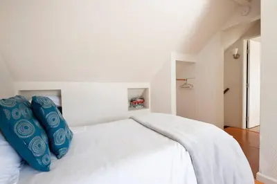 a white bed with blue pillows on top of it at 30 PCT OFF! Malibu Serene Cottage with King Bed, Beach, BBQ in Malibu