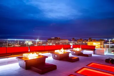 a rooftop patio with couches and tables at night at SW Beach Hotel in Hermosa Beach