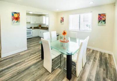 a dining room with a glass table and white chairs at Large Condo Sleeps 10 near Downtown Los Angeles in Los Angeles
