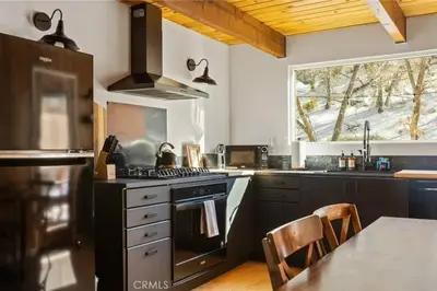 a kitchen with black appliances and a table and a window at Le Chalet of Arrowbear Lake in Running Springs